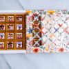 Real&Natural Raksha Bandhan chocolate gift box with 20 assorted chocolates in festive wrappers, displayed in a floral designer box with a transparent patterned lid."